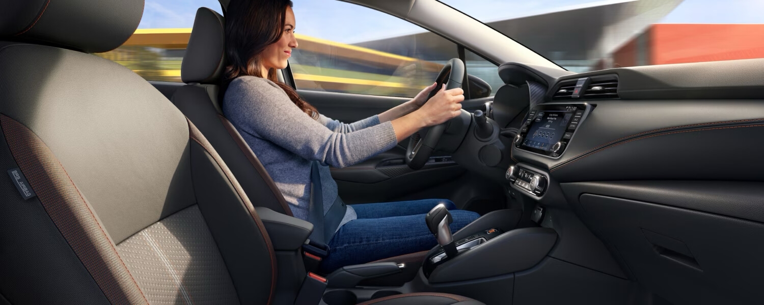 Femme au volant de la Nissan Versa 2025 incluant les technologies embarquées.