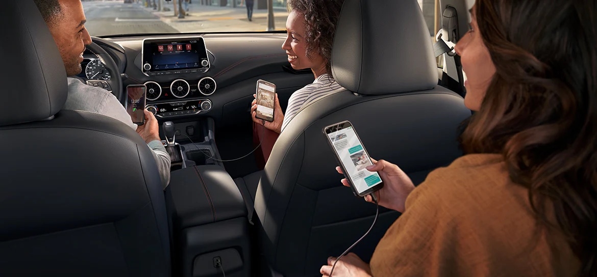 Passagers utilisant leur iPhone pour les assistants vocaux à bord de la Nissan Sentra 2025.